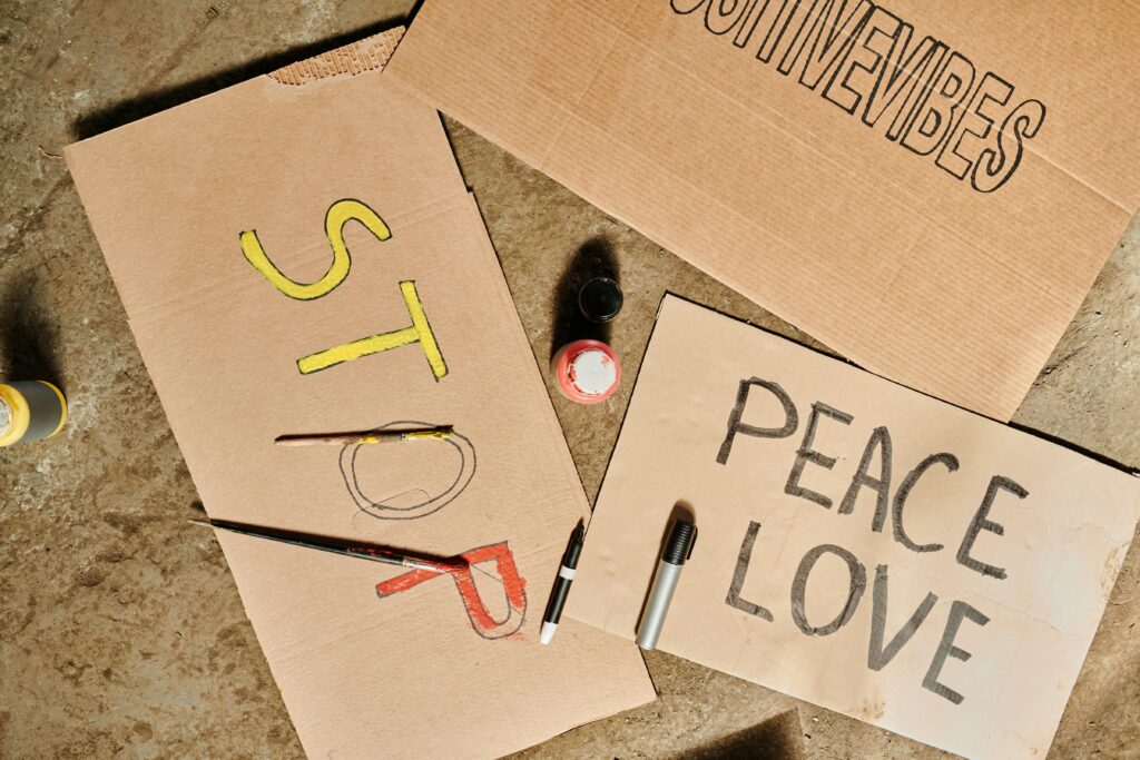 Close-up of handmade protest signs with words 'STOP' and 'PEACE LOVE' using paints and markers on cardboard.